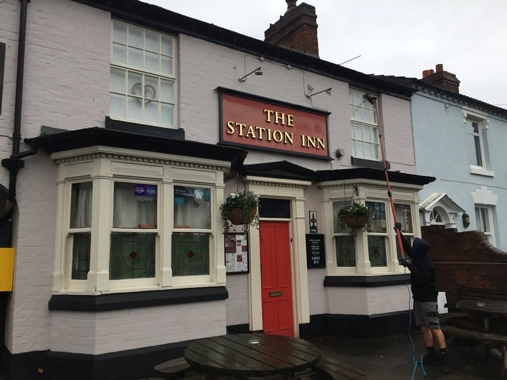 Cleaning the windows of The Station Inn pub with a pole