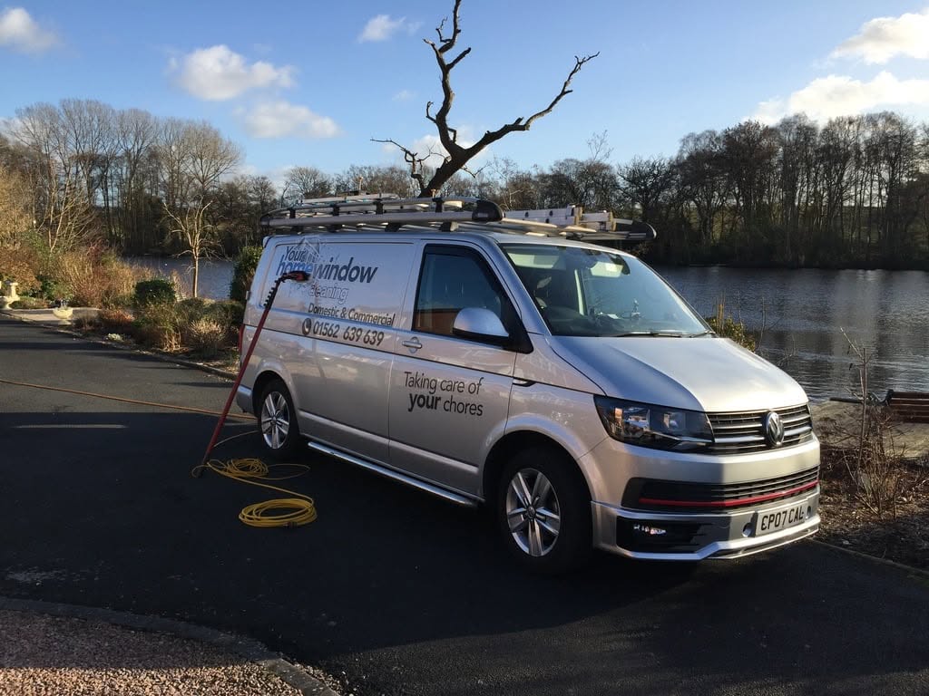 Company van beside a lake with hose reel and water-fed pole set up